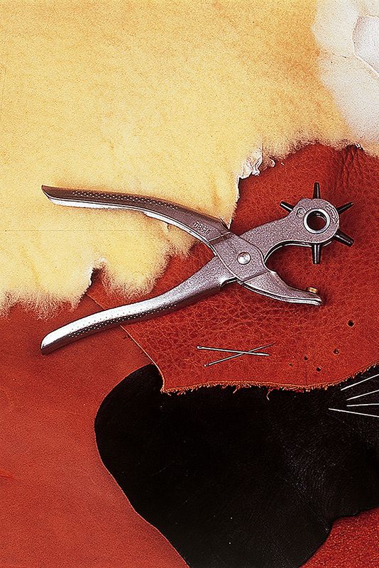 Lochzange Lochzange aus Metall auf rotem Leder und hellem Fell