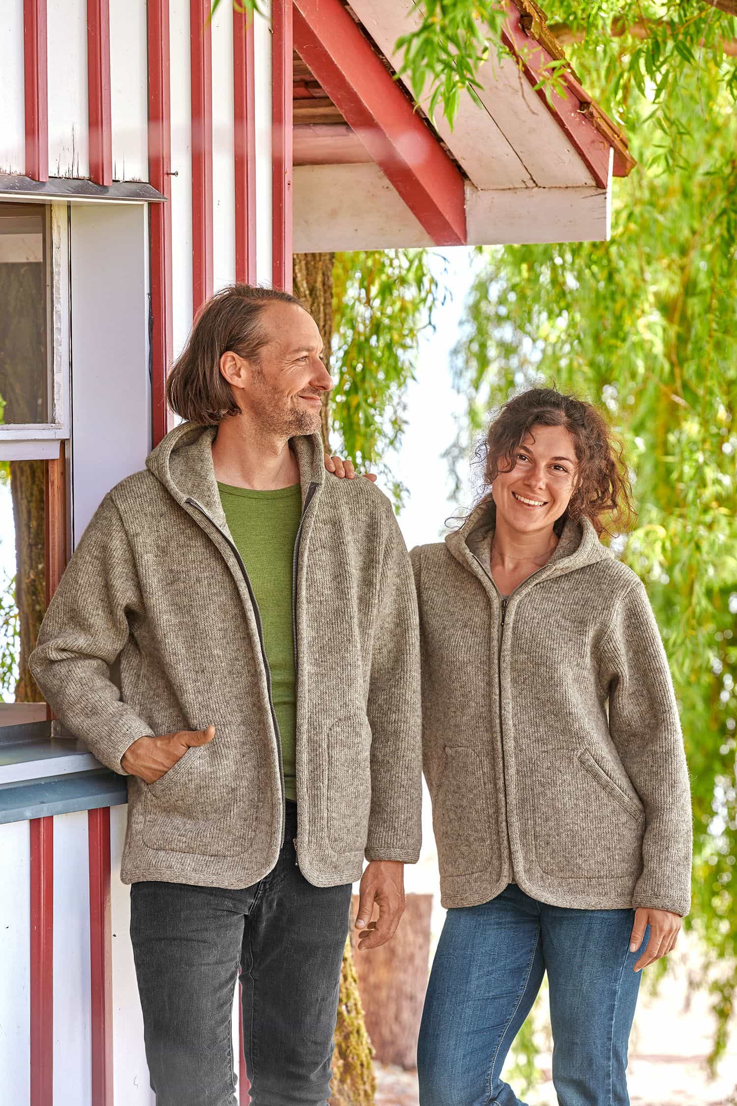 Mann und Frau tragen graue Finkhof Kapuzenjacken aus bio Wolle (kbT)