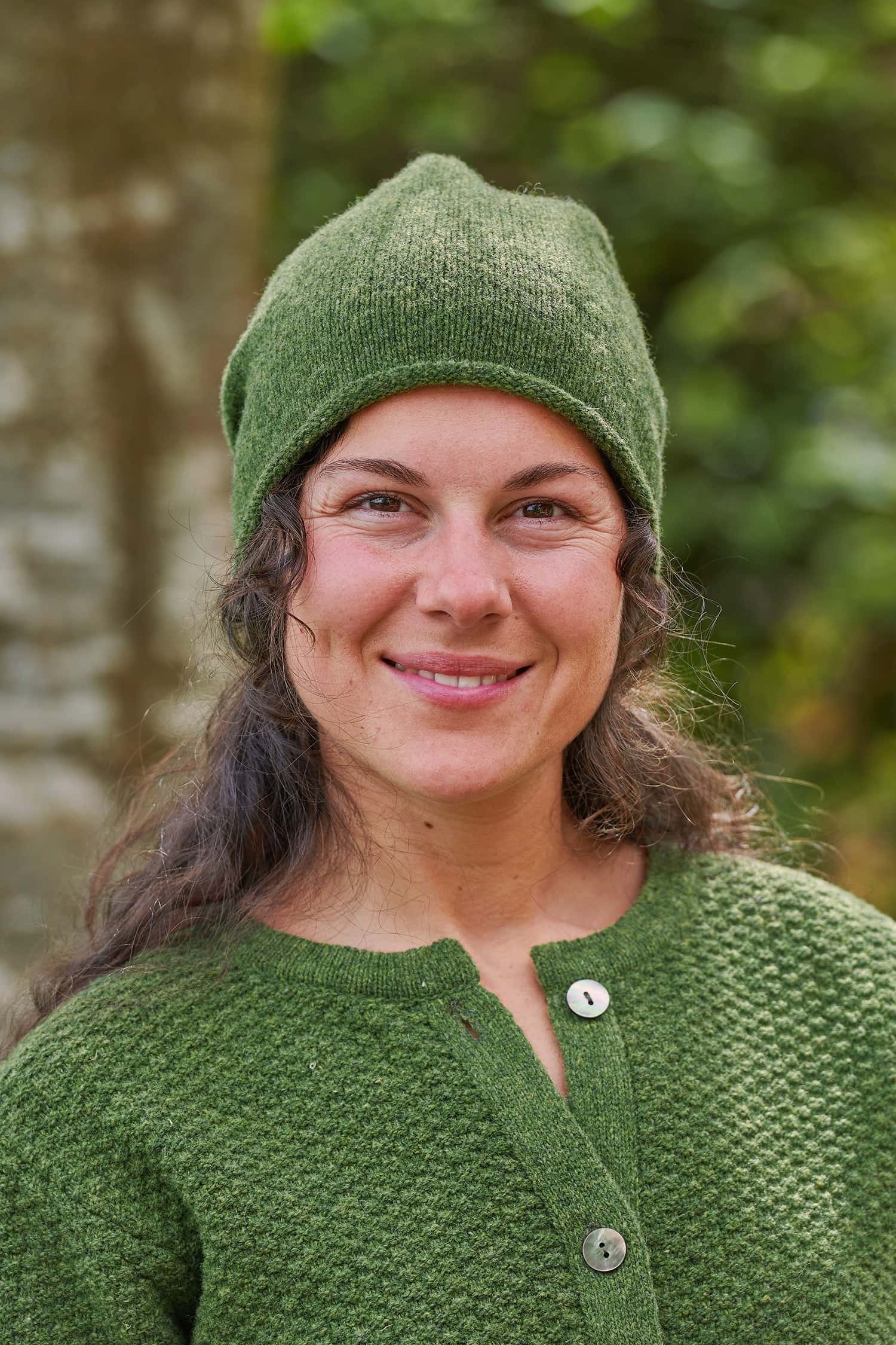 Frau trägt eine grüne Strickmütze mit Rollrand aus Bio-Wolle vom Finkhof mit passender Strukturjacke
