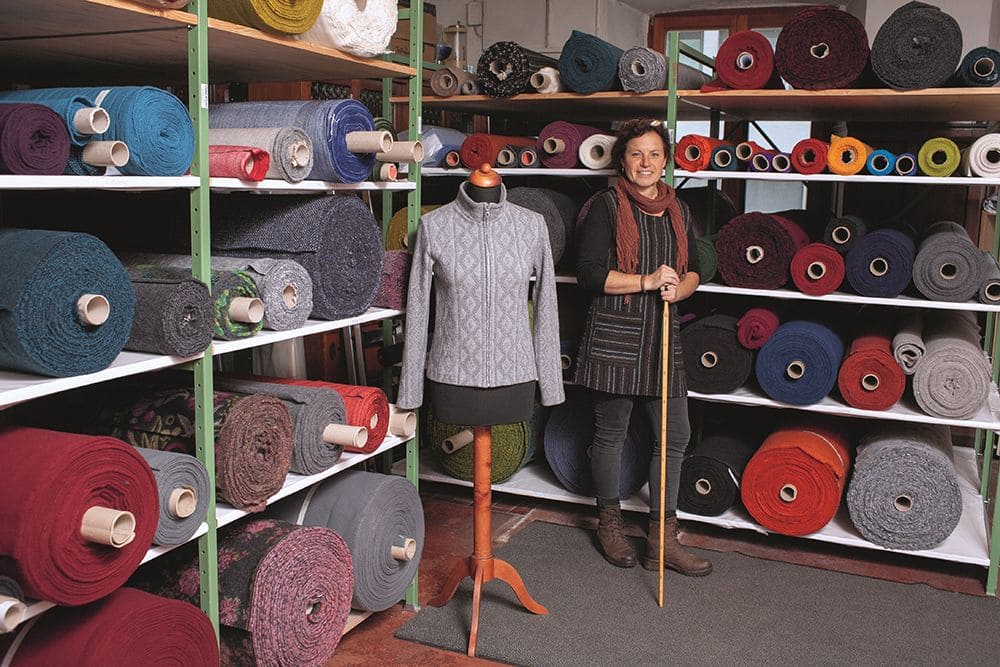 Frau steht in Finkhof Stoffatelier neben Regalen mit Stoffbahnen und Schneiderpuppe