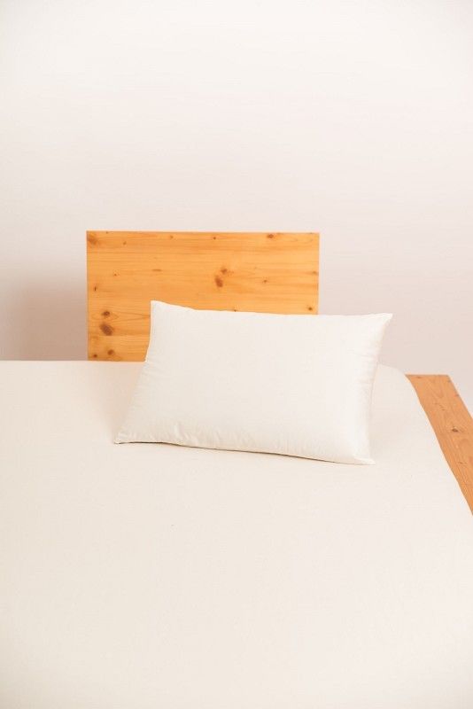 weißes Kopfkissen in 40x60cm aus bio Wolle (kbT) und bio Baumwolle (kbA) vom Finkhof auf hellbraunem Bett
