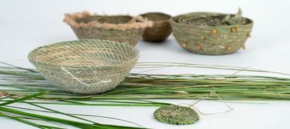 mehrere Graskörbchen mit Grashalmen auf weißem Untergrund