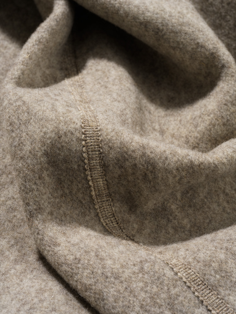 graue Finkhof Webborte aus bio Wolle (kbT) auf grauem Stoff angebracht