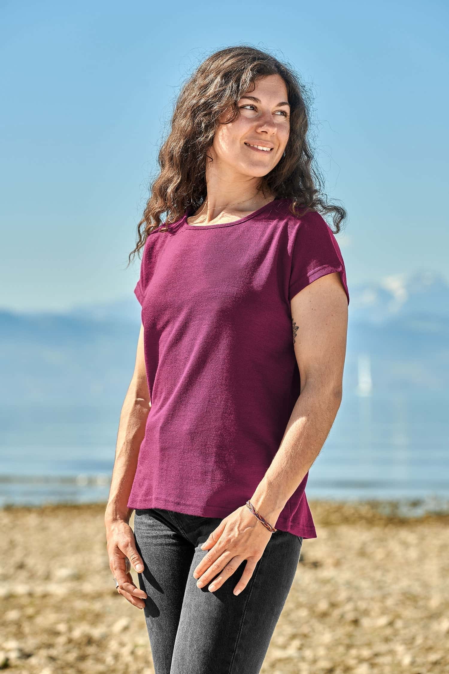 Seitliche Aufnahme von Frau, die ein pink lilanes Oversize Shirt aus Bio-Wolle und Seide vor einer Bergkulisse trägt
