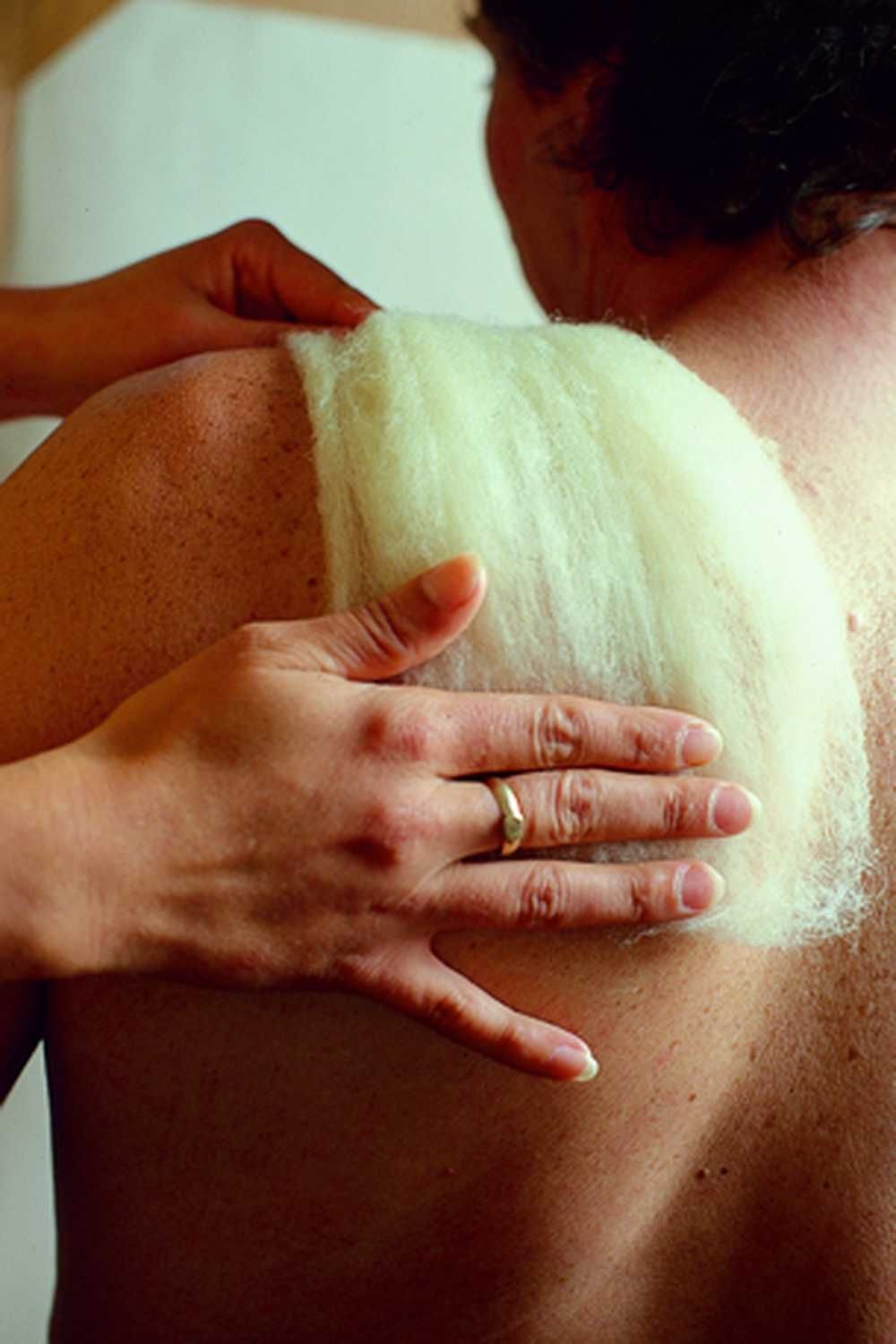 Stückchen Fettvlies aus bio Wolle (kbT) vom Finkhof wird auf Schulter ausgebreitet