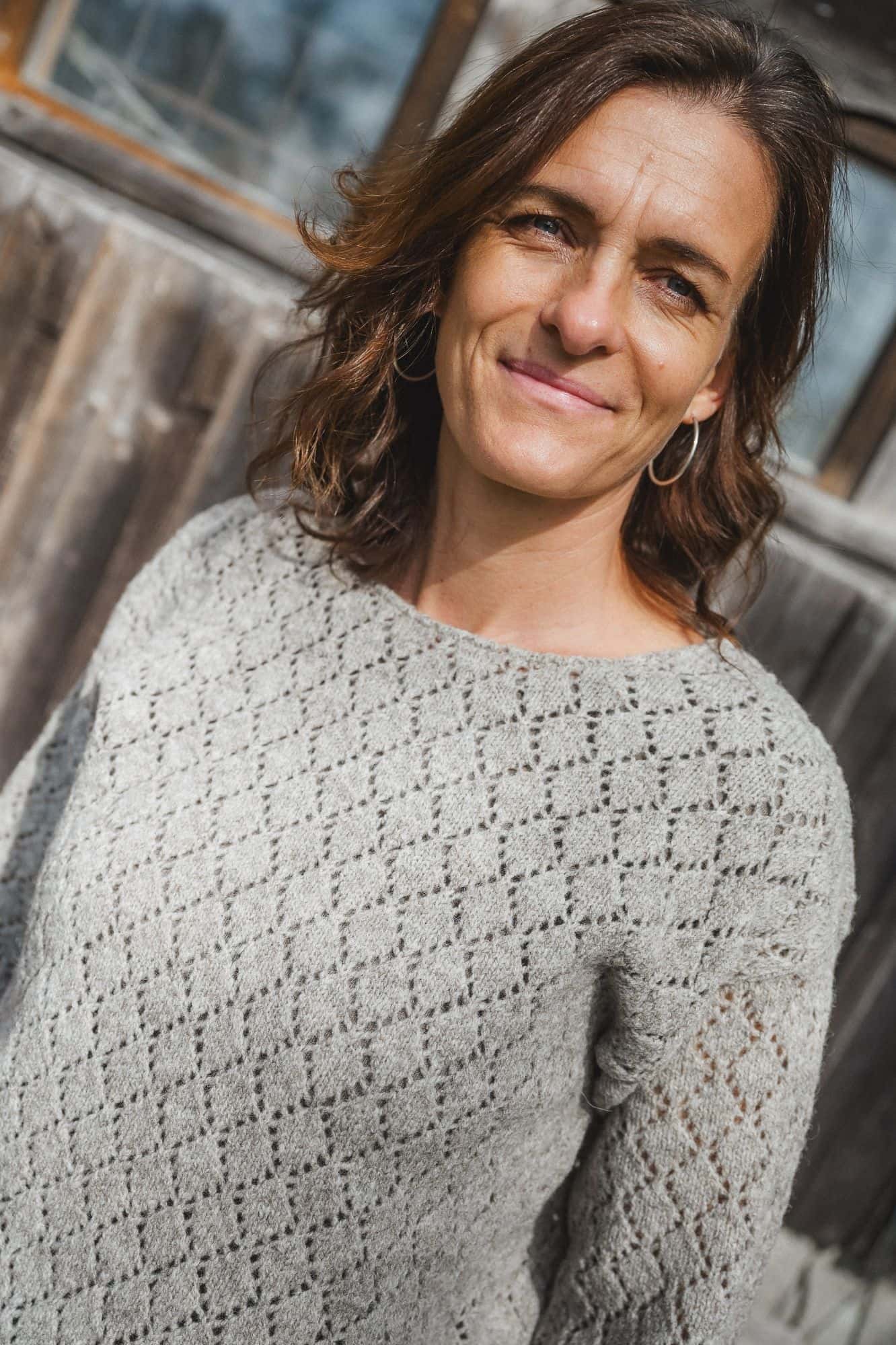 Frau trägt grauen ungefärbten Strickpullover mit Ajourmuster aus Bio-Wolle vom Finkhof