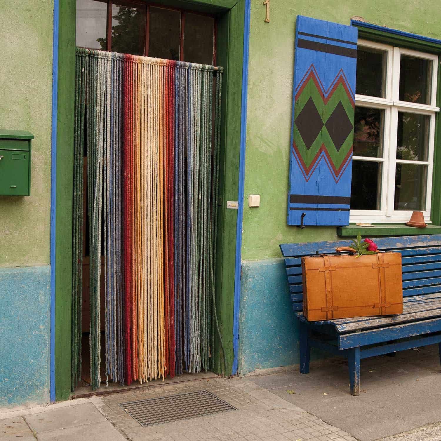 blau grünes Finkhof Gebäude mit buntem Türvorhang