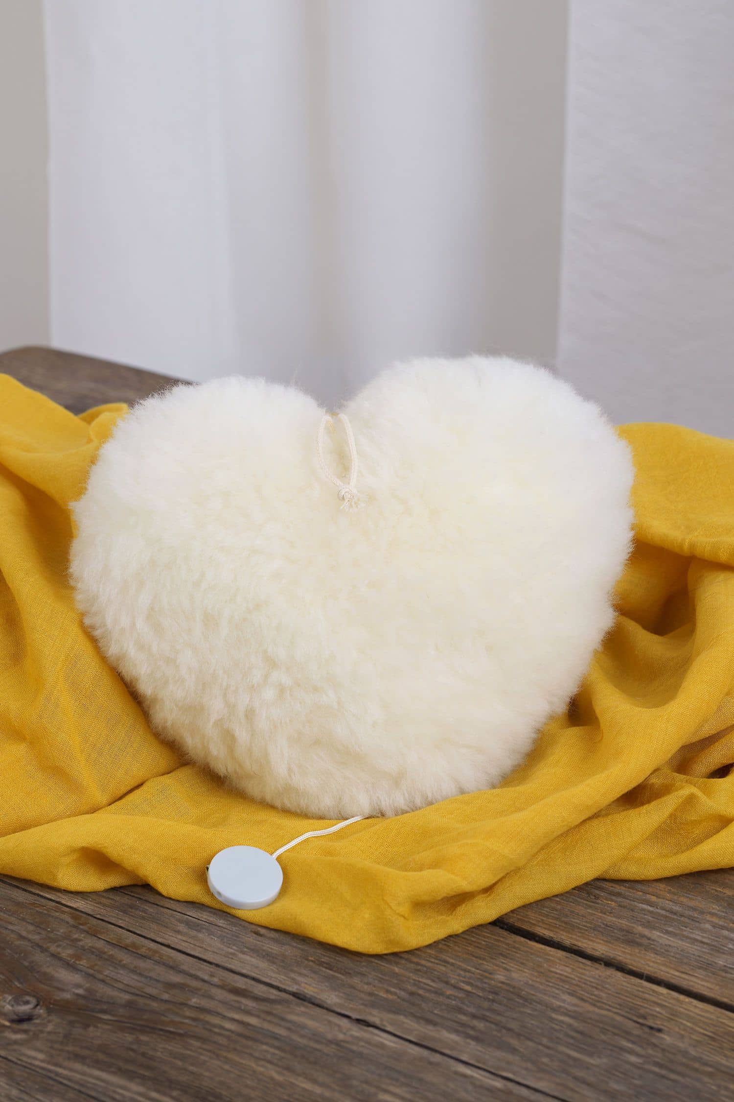 Spieluhr Herz weiße Spieluhr in Herzenform aus Schaffell mit bio Wolle (kbT) vom Finkhof auf gelber Decke