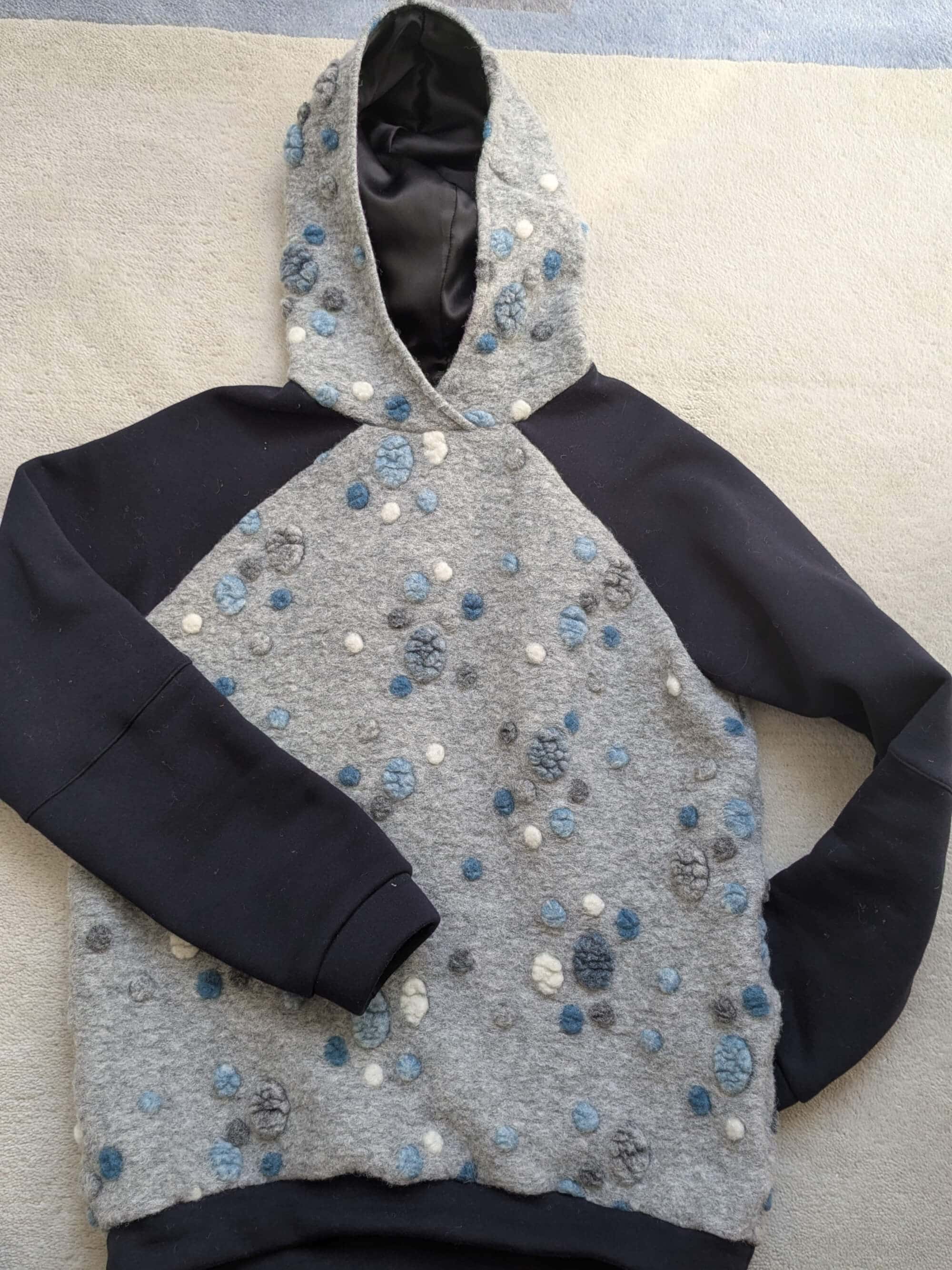 Hoodie liegend aus blau grau gepunktetem Musterwalk mit dunkelblauen Details