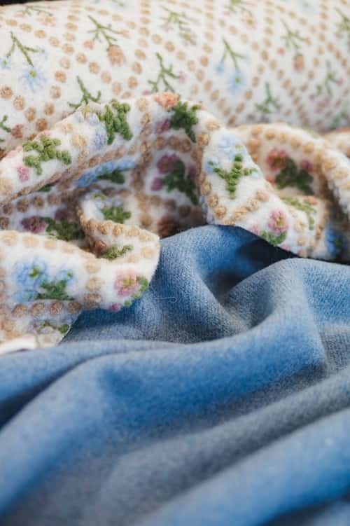 Heller Stoff mit Muster liegt neben einem rauchblauen Stoff