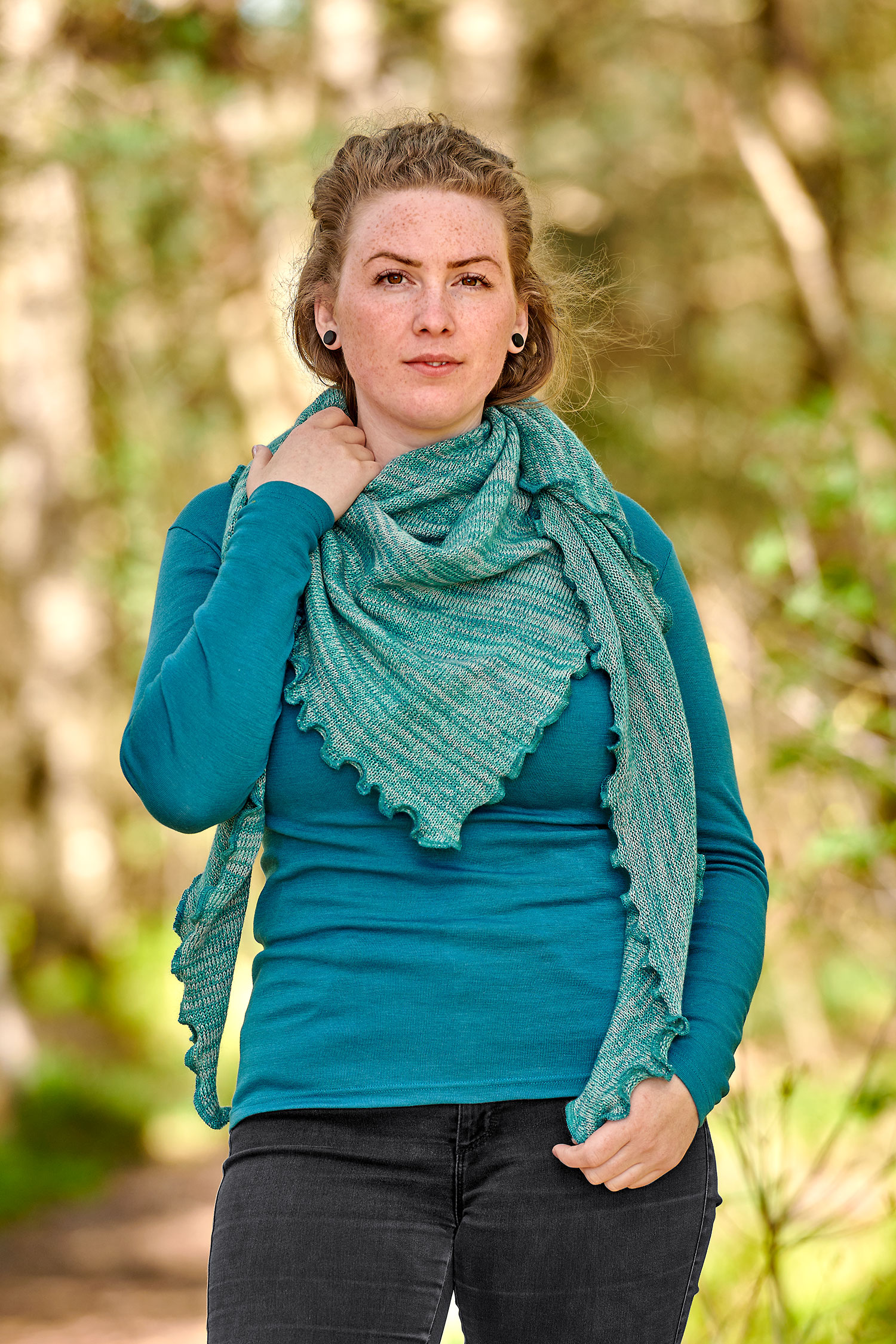 Frau mit türkisem Shirt trägt ein türkismeliertes Dreieckstuch aus bio Baumwolle (kbA) und bio Merinowolle (kbT)