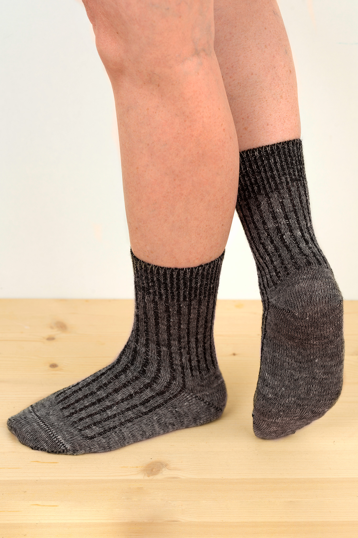 Wolle-Leinen-Socken graumeliert aus Bio-Schurwolle graumelierte bio Wolle (kbT)-Leinen- Socken getragen von 2 Menschen mit nacktem Bein im Stehen