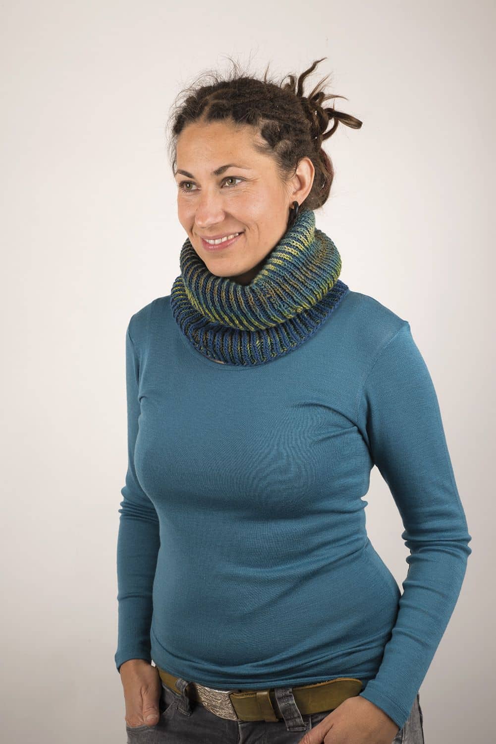 Frau trägt blaues Shirt und blau grün gestrickten Loopschal