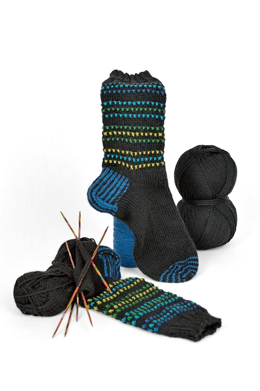 feine schwarze Finkhof Sockenwolle aus bio Wolle (kbT) als Knäule und fertiger Stricksocke mit Farbakzenten