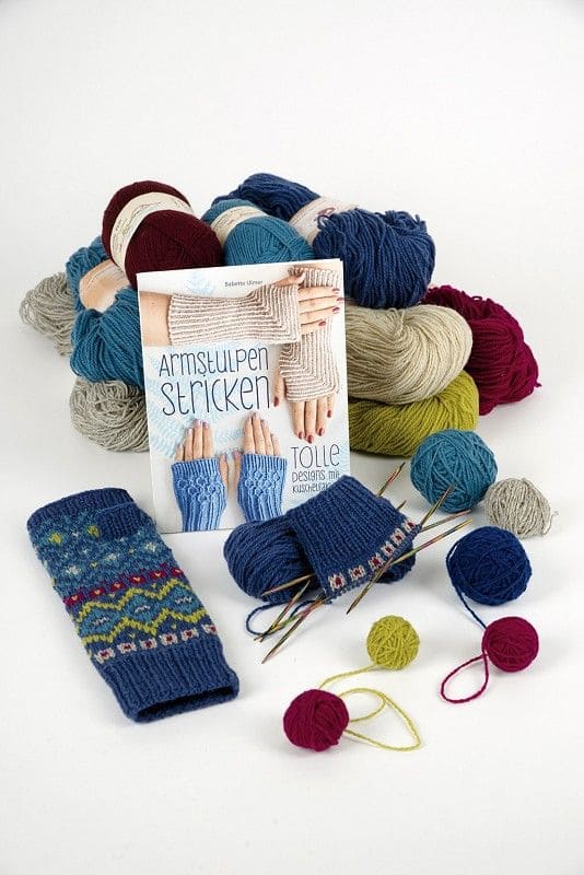 Armstulpen stricken Buch ,,Armstulpen stricken" auf Stimmungsbild mit verschiedenfarbigen Wollknäulen und gemusterten Armstulpen