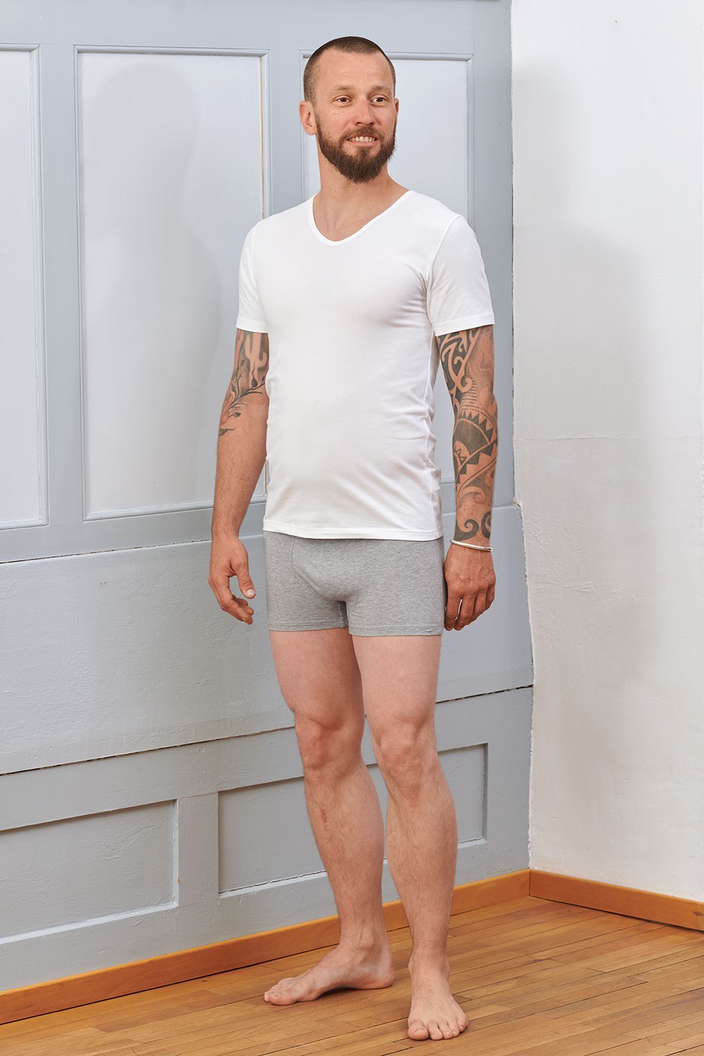 Baumwoll-Herren-Kurzarmshirt aus Bio-Baumwolle Mann trägt graue Boxershorts und ein weißes Kurzarmshirt aus bio Baumwolle (kbA) und Elasthan mit V Ausschnitt