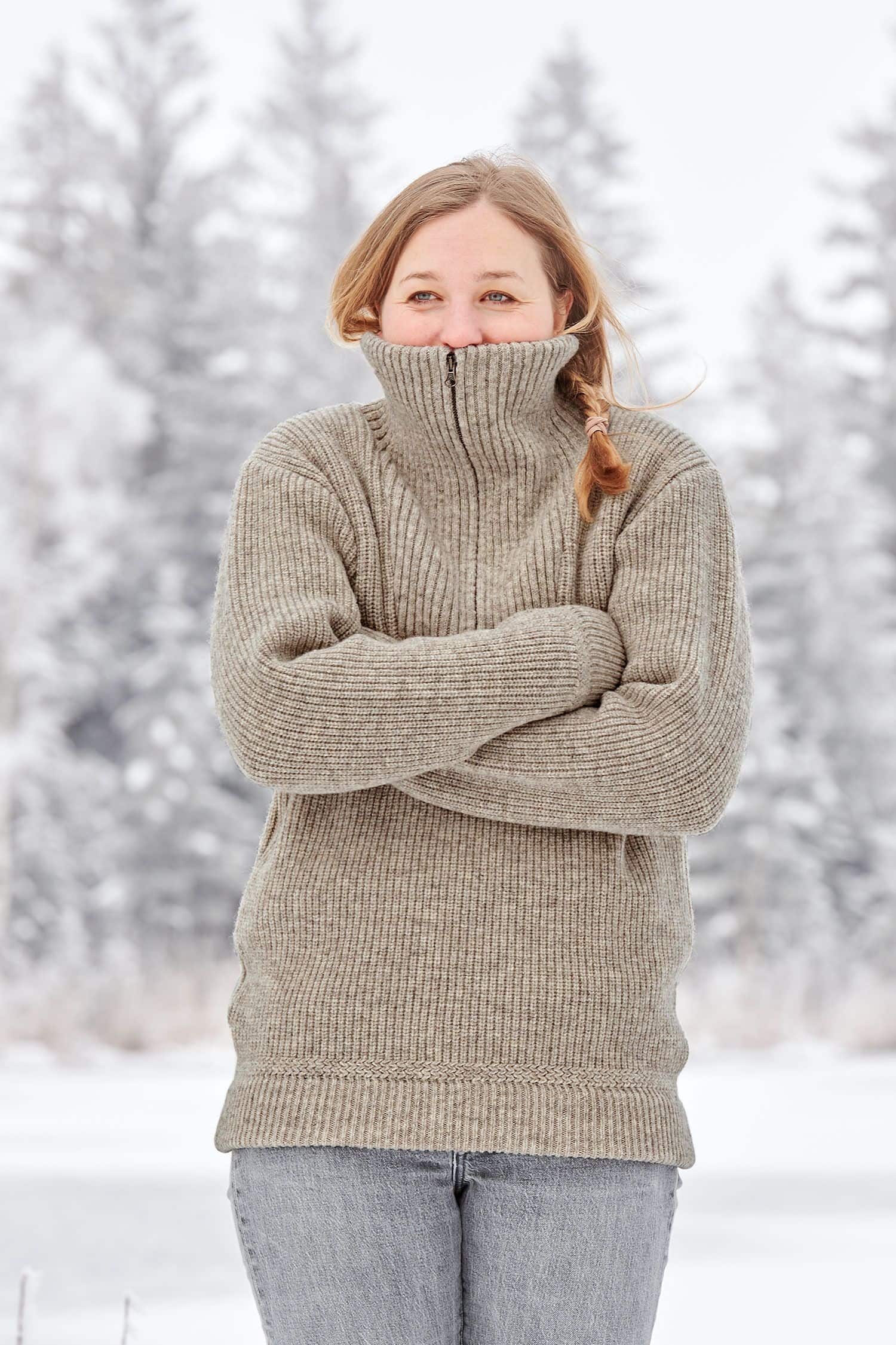 Frau kuschelt sich in grauen Finkhof Troyer aus bio Wolle (kbT) vom Merinolandschaf in winterlicher Landschaft
