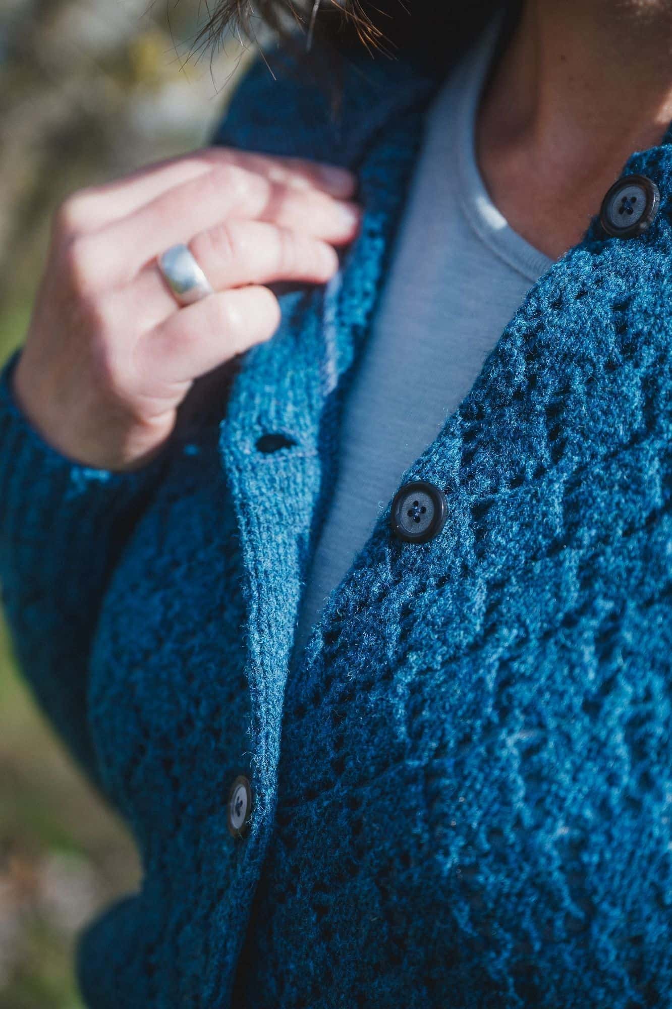 Nahaufnahme der Knopfleiste der blauen Damenstrickjacke mit Ajourmuster aus Bio-Wolle vom Finkhof
