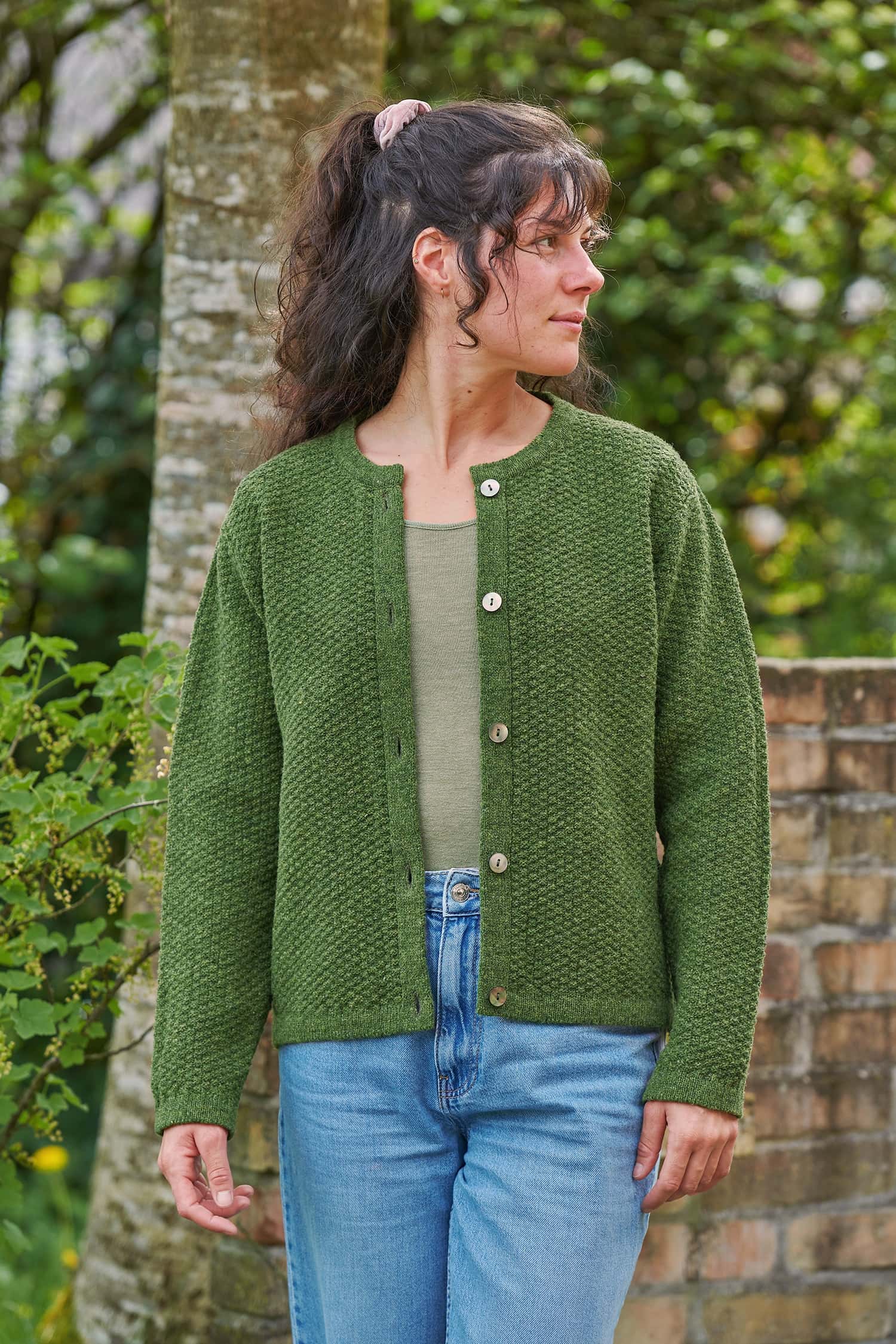 Finkhof-Strukturjacke aus reiner Bio-Schurwolle Frau trägt eine blaue Jeans, ein grünes Shirt und eine grüne Strukturjacke aus Bio-Schurwolle vom Finkhof