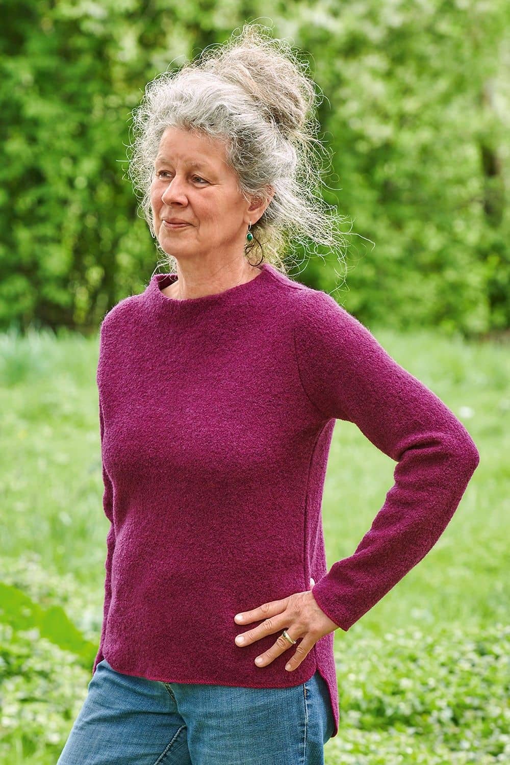 Pulli Frieda fuchsia Gr. M Frau mit Jeans im Grünen trägt pinken Pulli aus bio Wolle (kbT)