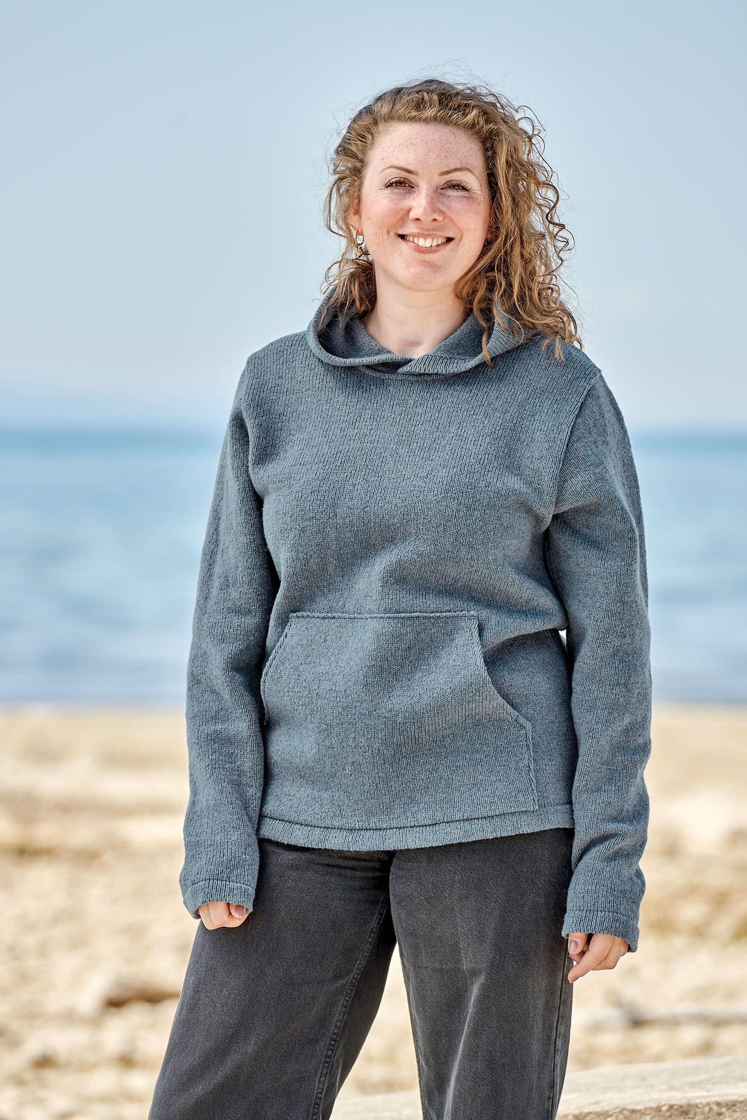 Frau trägt rauchblauen Kapuzenpullover aus bio Merinowolle (kbT) vom Finkhof