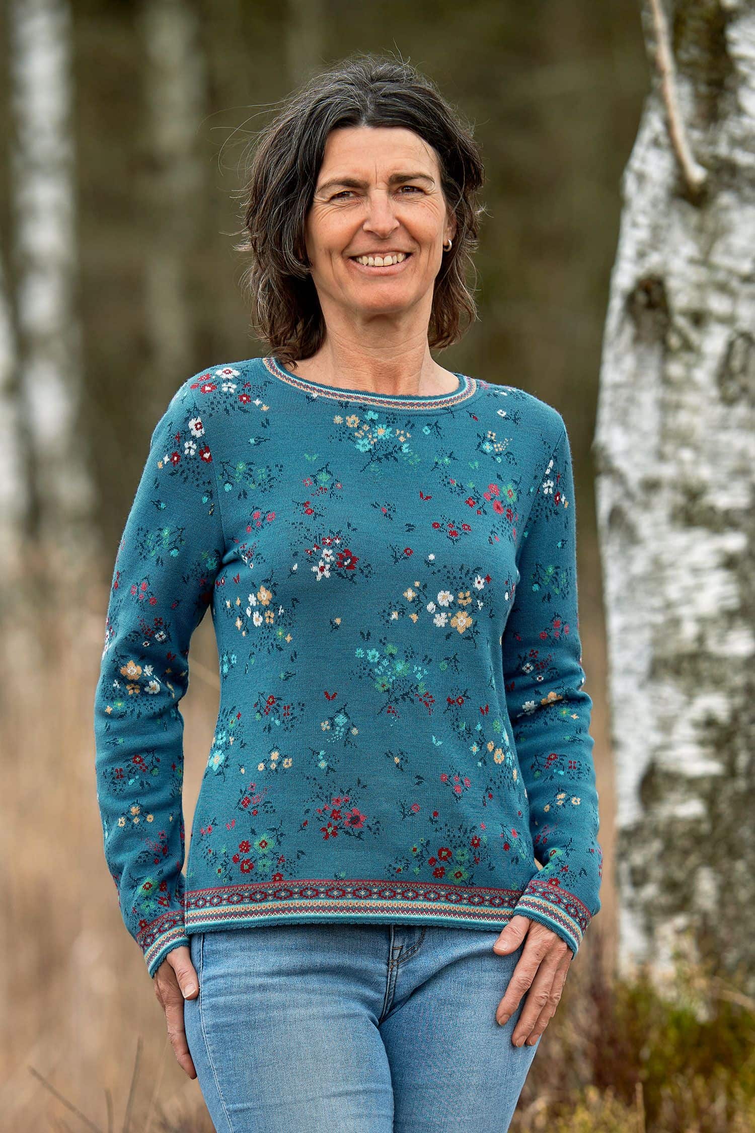 Frau steht draußen und trägt blau geblümten Pullover