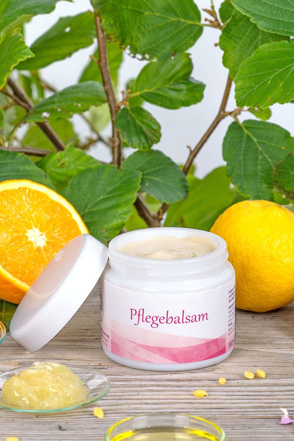 Pflegebalsam 100 ml Geöffneter Pflegebalsam im Glastiegel vom Finkhof – Naturkosmetik mit Wollwachs & Olivenöl, inszeniert mit Orange und Blättern