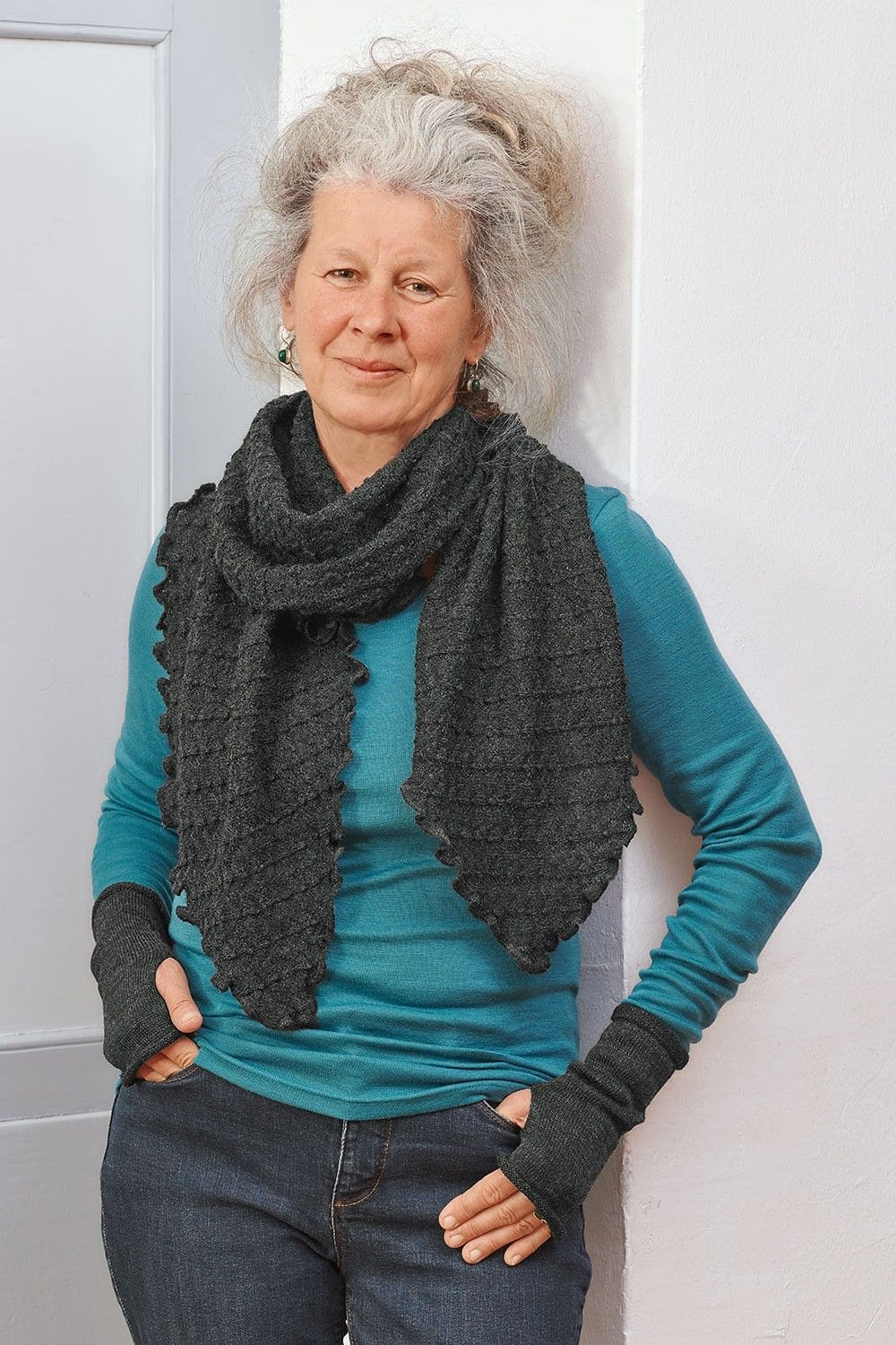 Frau trägt türkises Shirt und dunkelgraue Handstulpen aus bio Wolle (kbT) vom Finkhof und einen anthrazitfarbenen Ajourschal