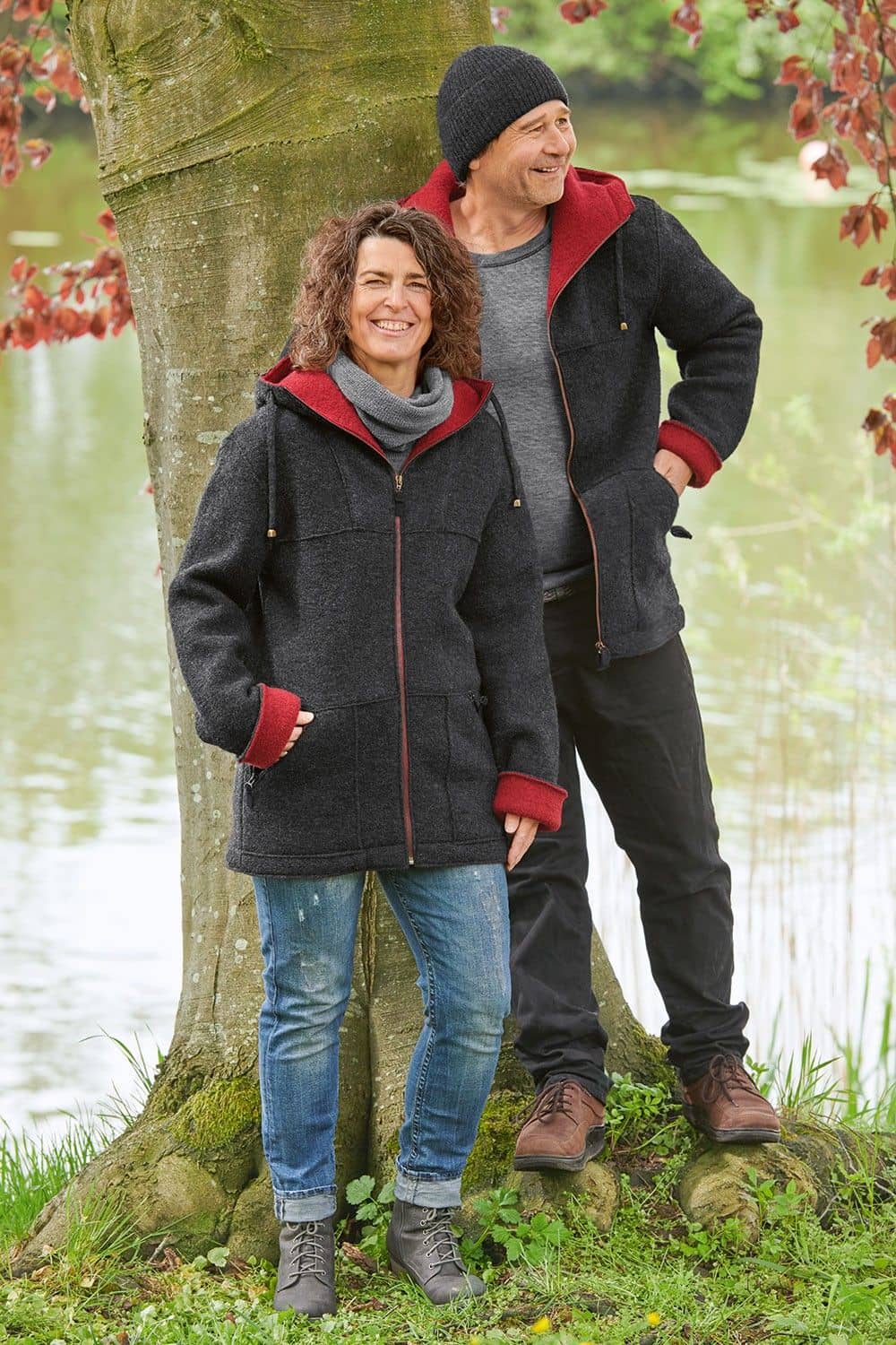 Jacke Chris aus reiner Bio-Schurwolle Mann und Frau tragen anthrazitgraue Jacke mit Kapuze und rotem Innenfutter aus bio Wolle (kbT) vom Finkhof