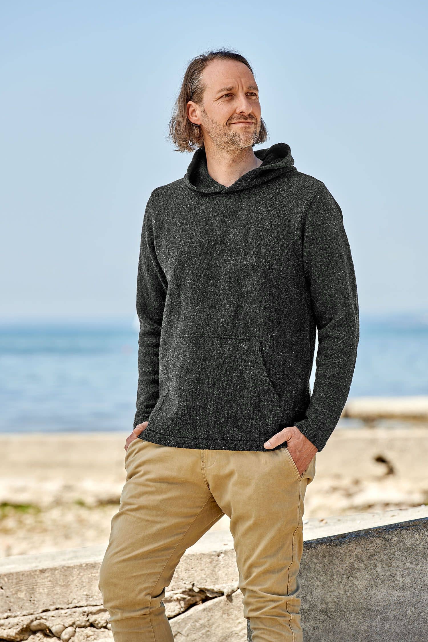 Finkhof-Kapuzenpulli anthrazit Gr. XL Mann trägt anthrazitfarbenen Kapuzenpulli aus bio Merinowolle (kbT) vom Finhkhof